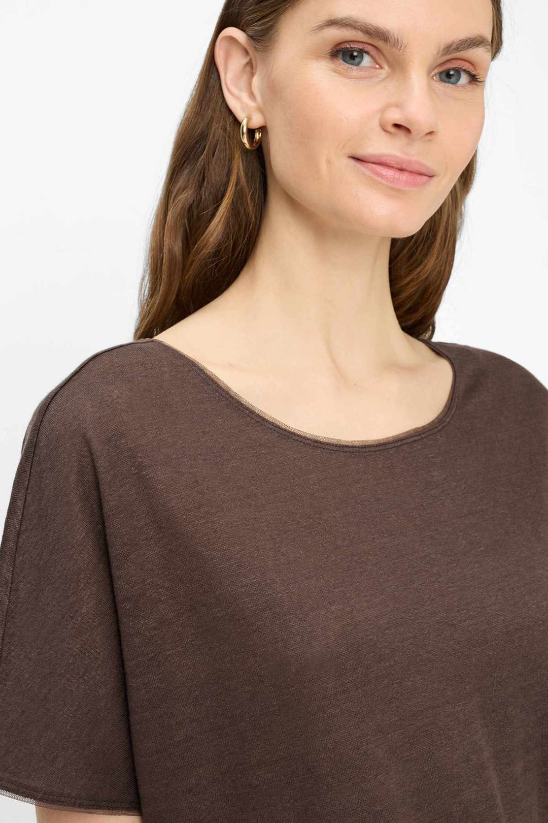 Femme portant le T-shirt col bateau Caelen à encolure dégagée et manches courtes, couleur marron, pour un look moderne et décontracté.