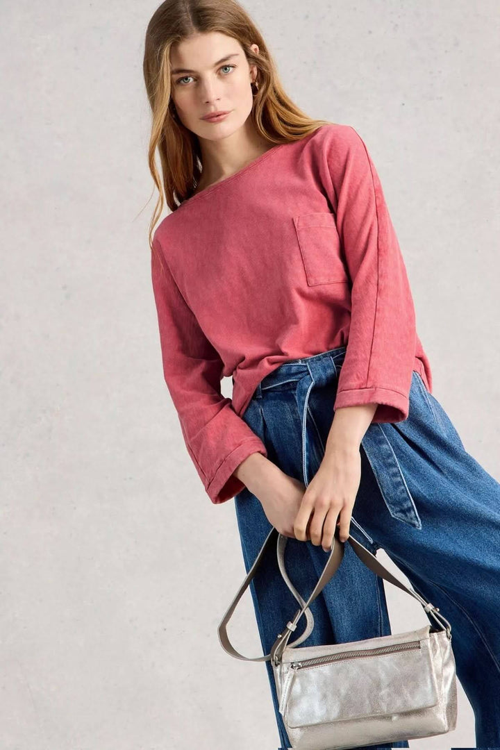 Femme portant un T-shirt à col rond demi-dos rouge avec manches trois-quarts et poche, combiné avec un jean bleu et un sac argenté.