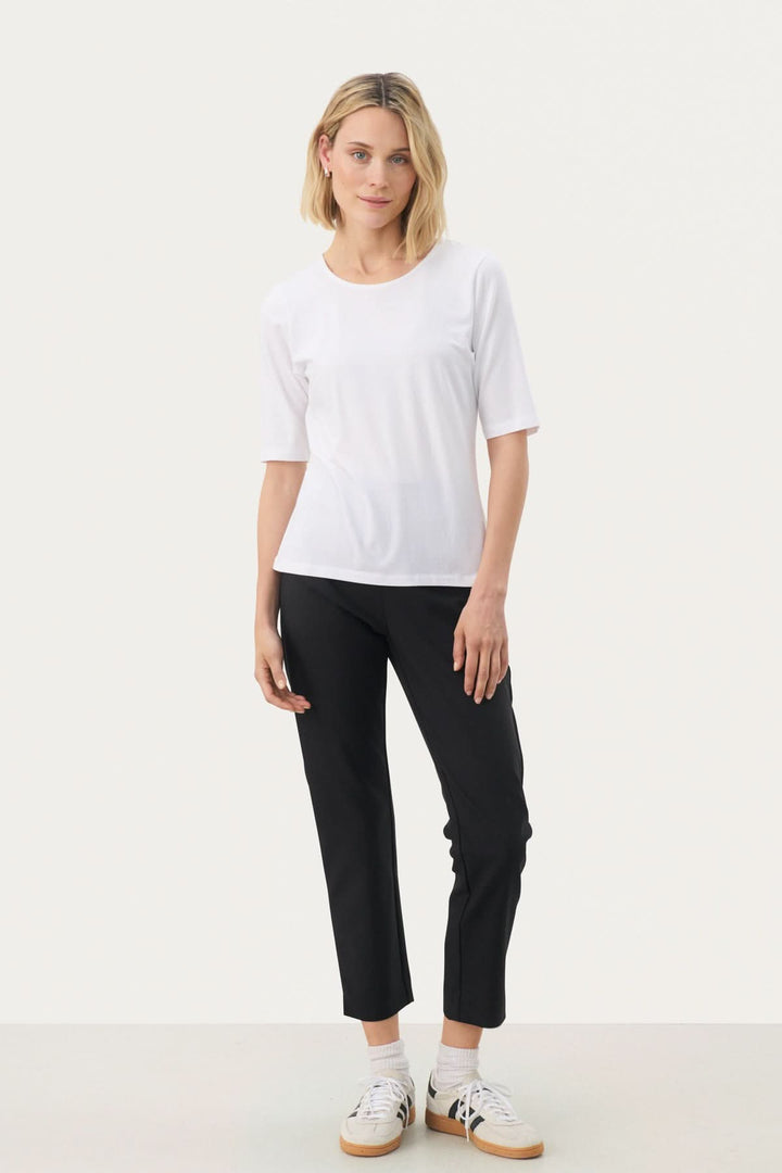 Femme portant un T-shirt coupe droite Nemi blanc, style épuré et minimaliste, idéal pour tenues modernes et polyvalentes.