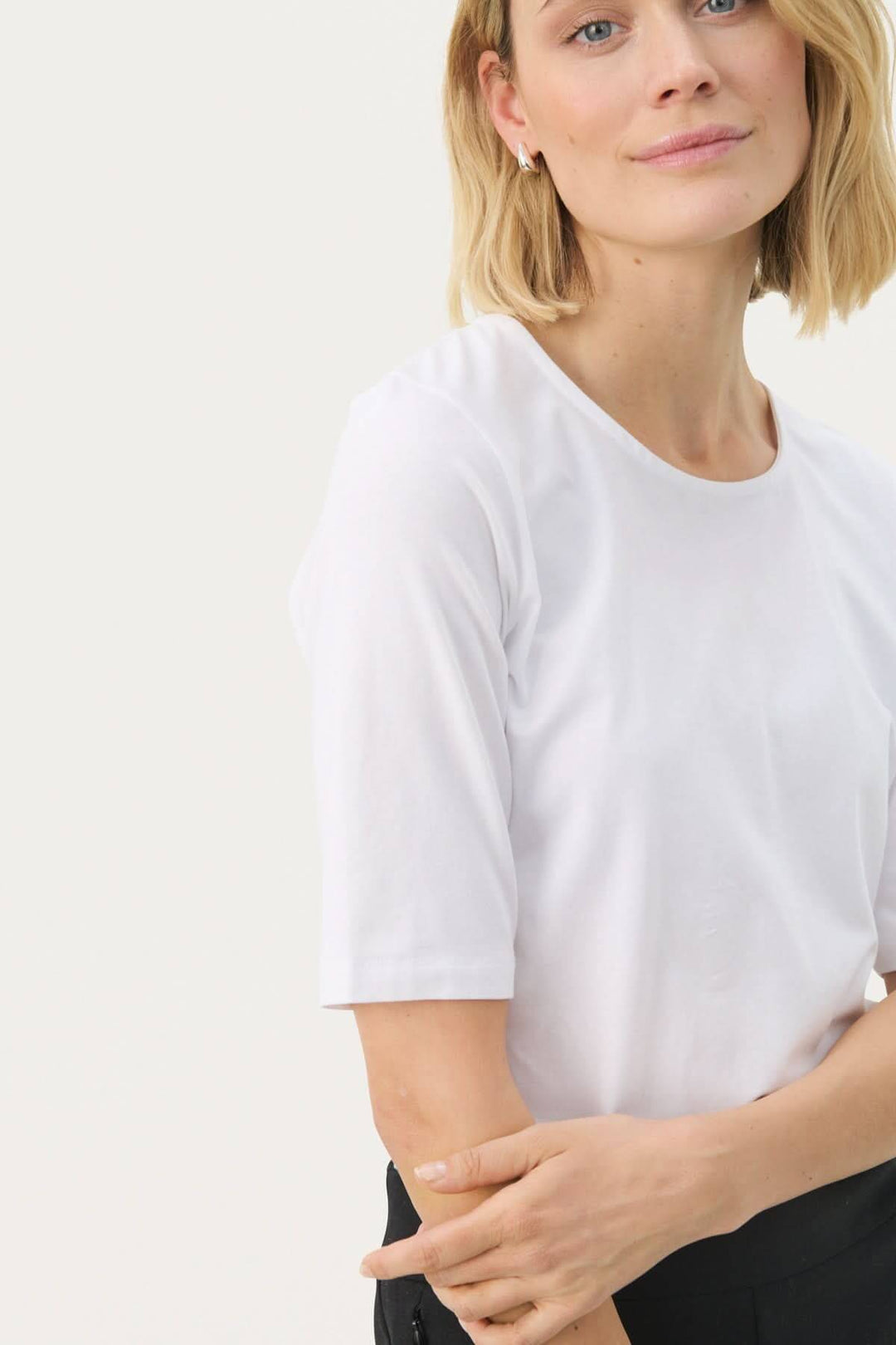 Femme portant le T-shirt coupe droite Nemi blanc, design minimaliste et silhouette épurée idéale pour des looks modernes quotidiens.