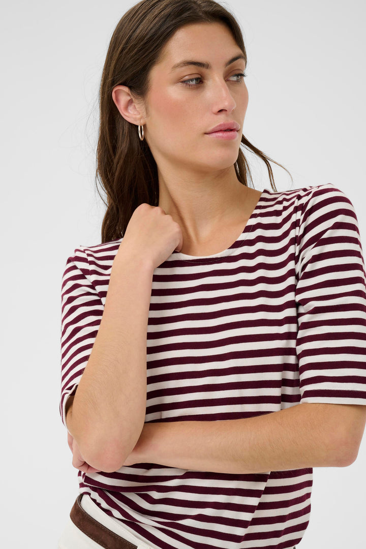 Femme portant un t-shirt à rayures marron et blanc, style décontracté élégant.