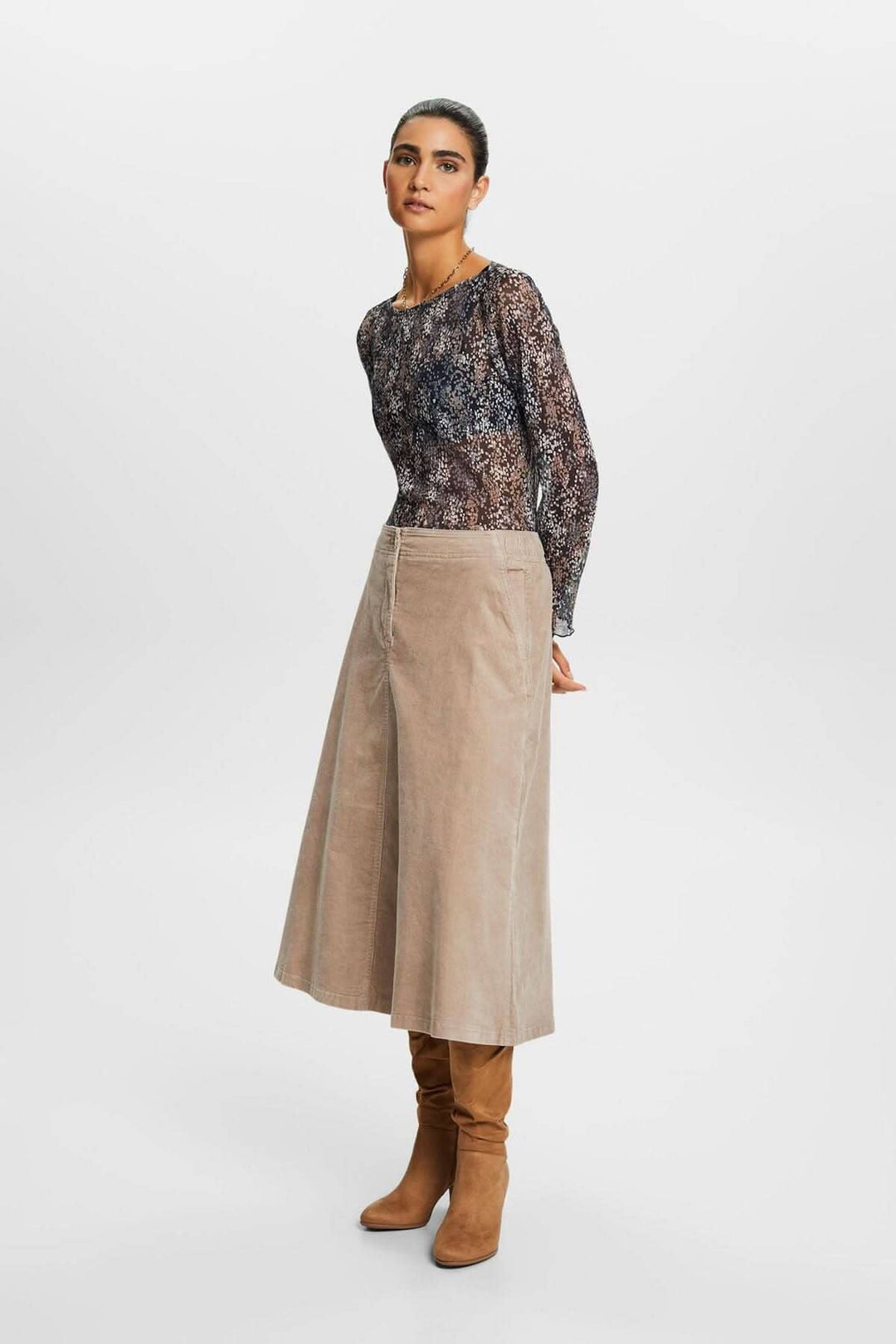 Femme portant un t-shirt en mesh plissé à motif avec jupes longues et bottes élégantes.