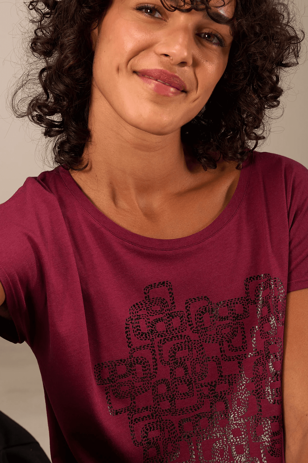 Femme portant un t-shirt imprimé avec manches courtes et col rond, graphique moderne sur le devant.