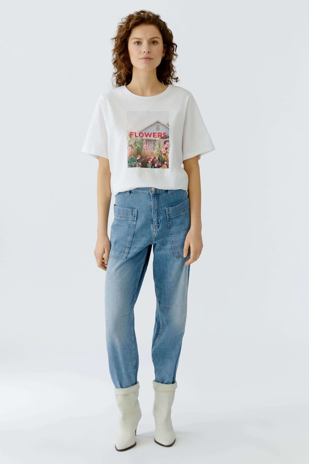 Femme portant un T-shirt imprimé graphique avec des fleurs, coupe droite, manches courtes, encolure ronde, style moderne et décontracté.