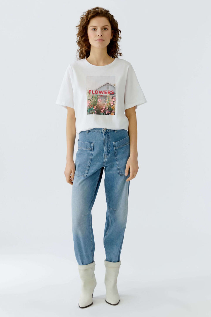 Femme portant un T-shirt imprimé graphique avec des fleurs, coupe droite, manches courtes, encolure ronde, style moderne et décontracté.