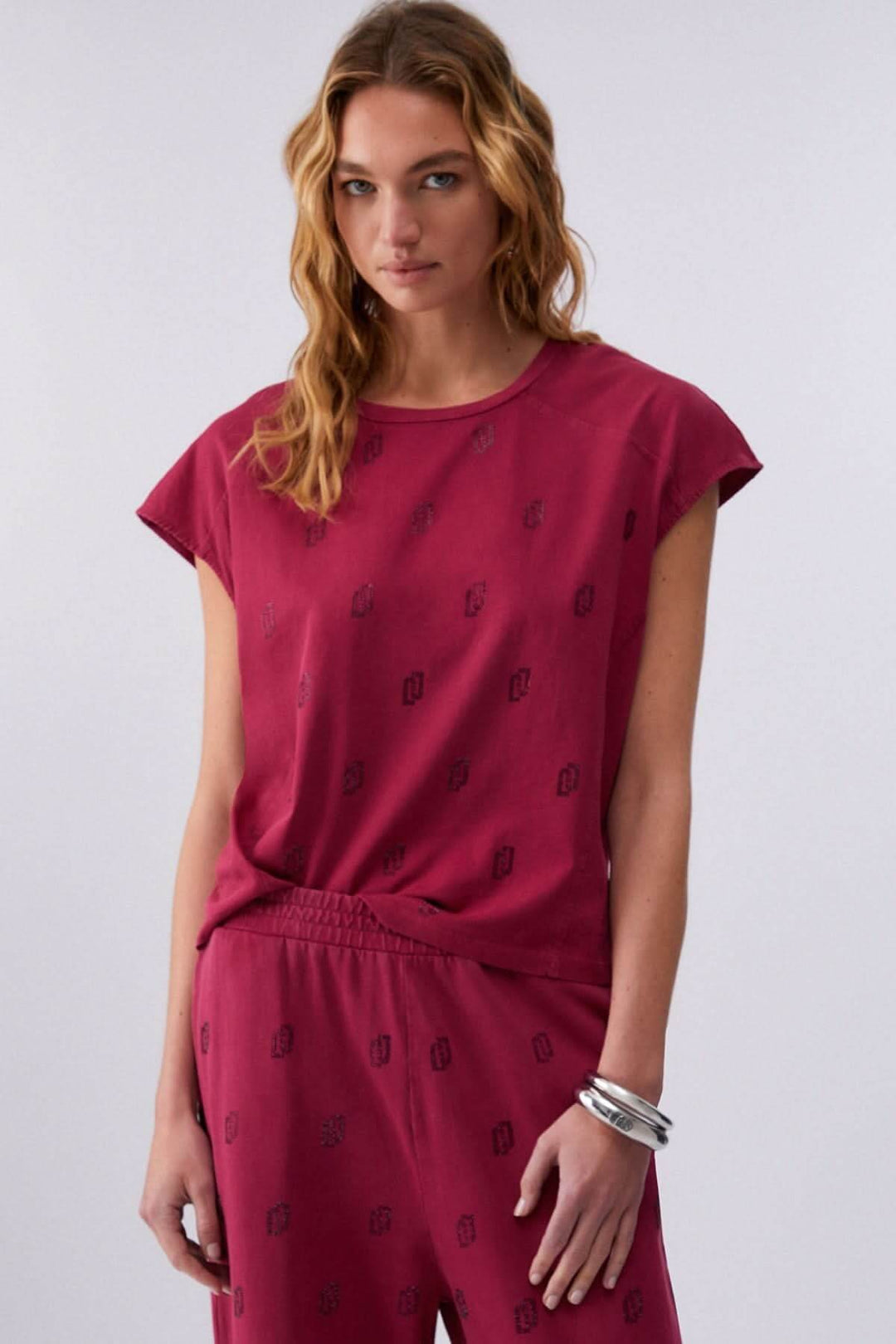 Femme portant un t-shirt imprimé à manches courtes rose avec motif discret et coupe décontractée, tenue moderne et confortable.