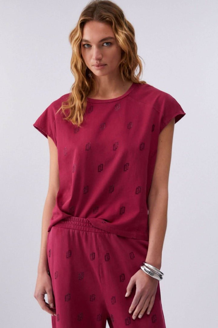 Femme portant un t-shirt imprimé à manches courtes rose avec motif discret et coupe décontractée, tenue moderne et confortable.