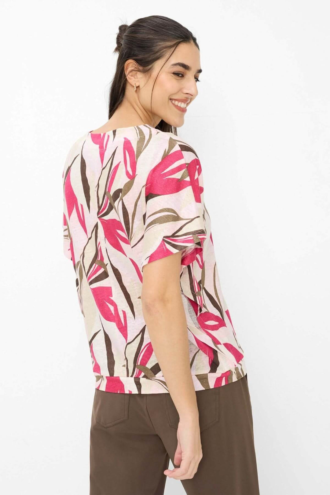 Femme portant le T-shirt imprimé végétal Cassie avec manches courtes et encolure en V, montrant le motif floral dans des tons vifs.
