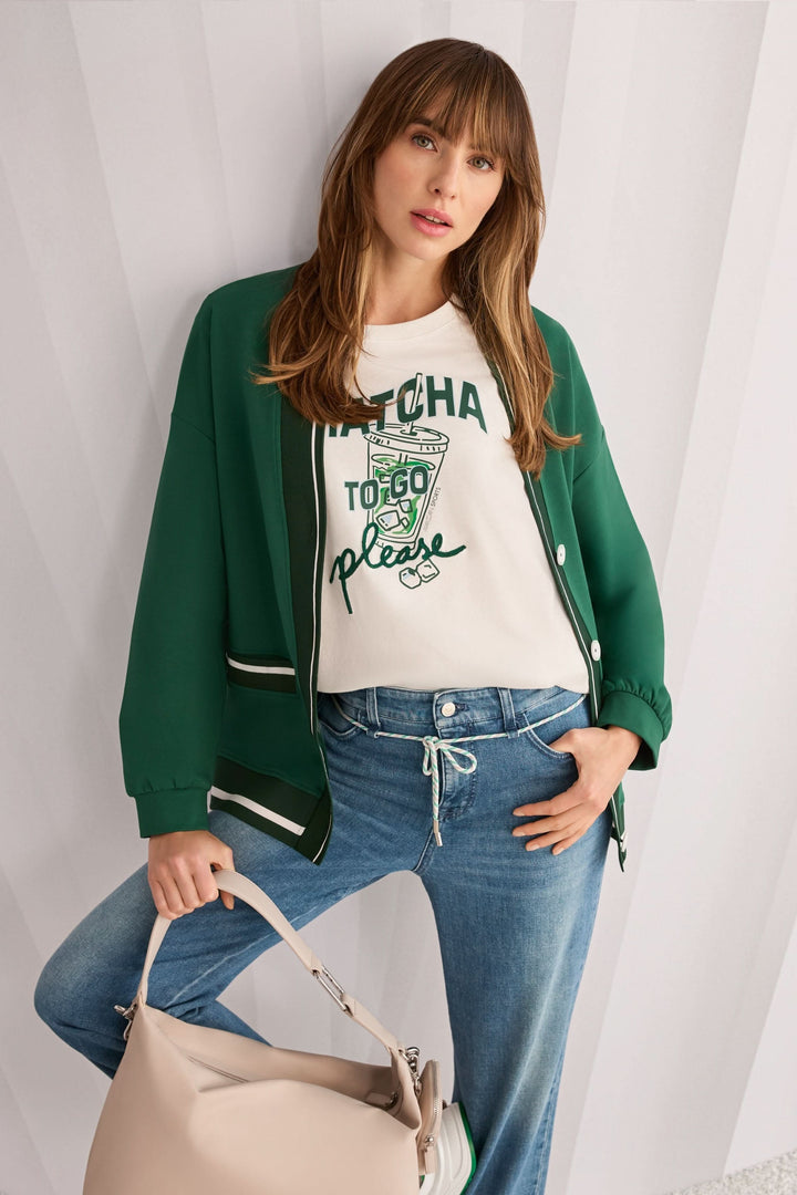 Femme portant un T-shirt imprimée matcha « Rethink Together » avec veste verte et jeans, accessoirisé d&