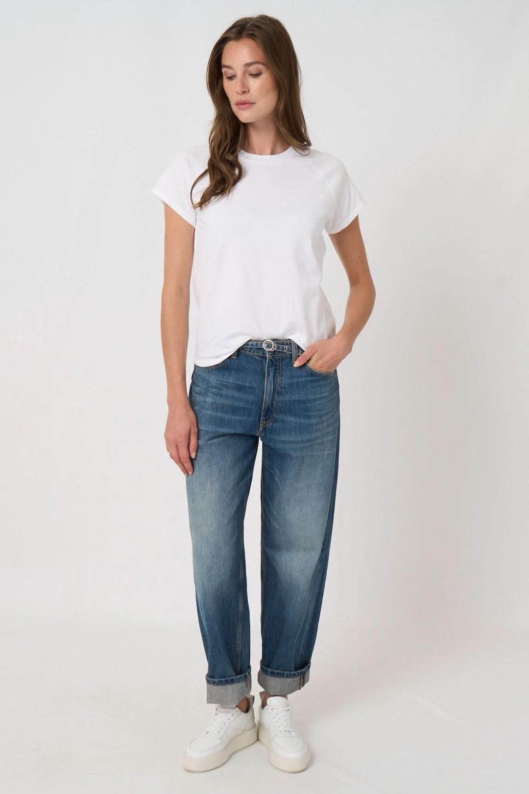 Femme portant un T-shirt à manches courtes blanc avec un jean et des baskets, style décontracté et confortable idéal pour le quotidien.