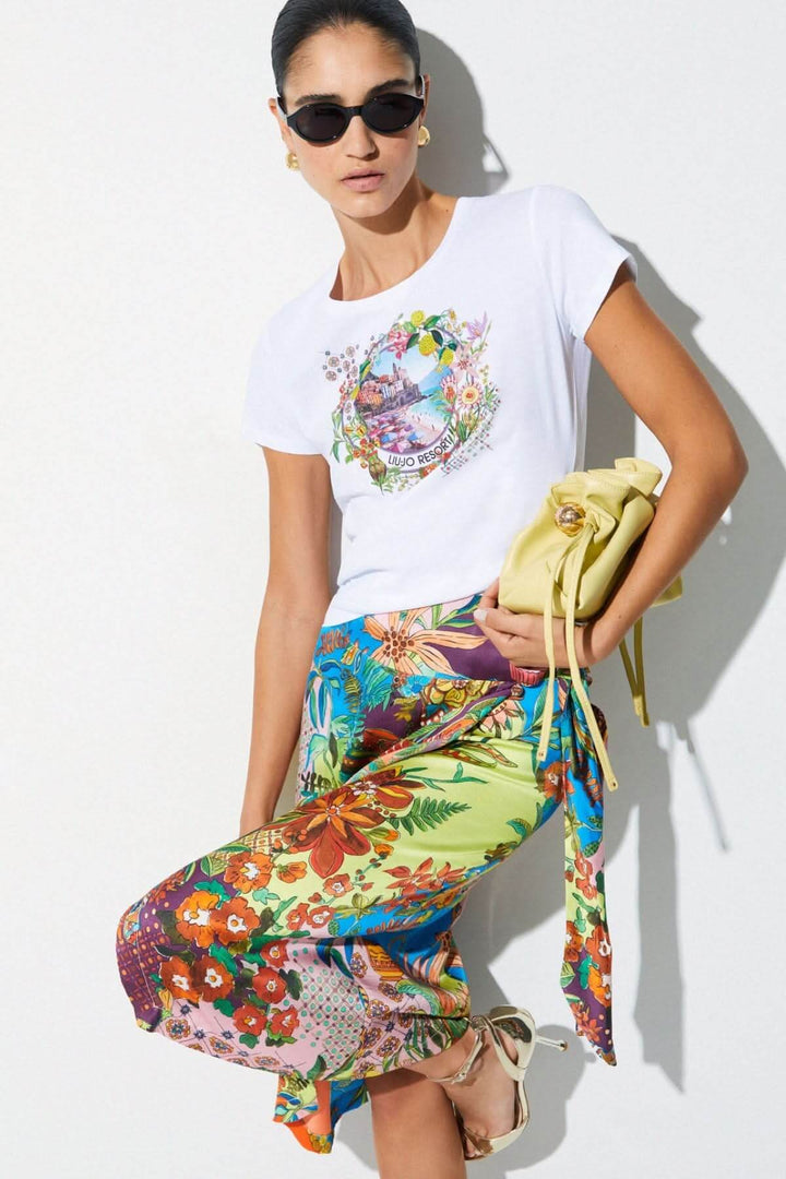 Femme portant un T-shirt à manches courtes avec imprimé graphique, jupe colorée et sac à main, tendance et décontracté.