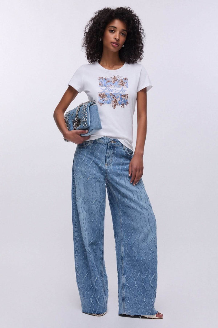 Femme portant un T-shirt à manches courtes avec imprimé graphique, complétant un look décontracté et moderne avec un jean large.