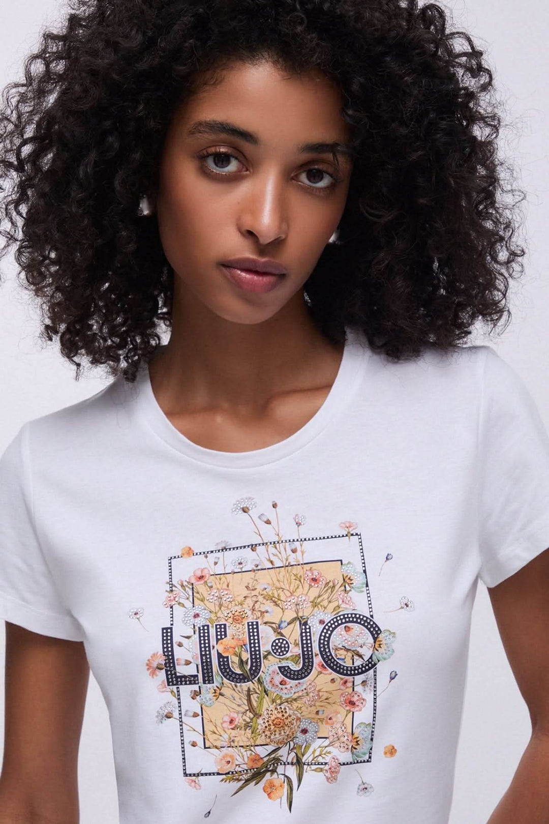 Femme portant un t-shirt à manches courtes avec imprimé graphique floral élégant, idéal pour une tenue décontractée et stylée.