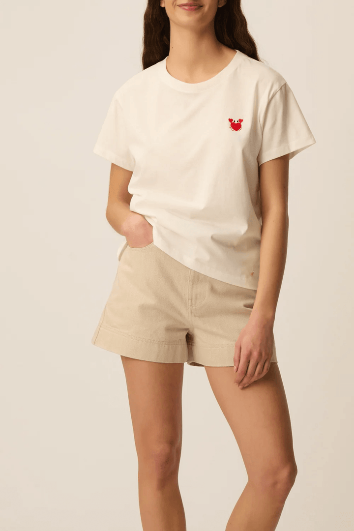 Femme portant un T-shirt à manches courtes col rond coupe classique en tissu doux, avec détail discret sur la poitrine, tenue casual.