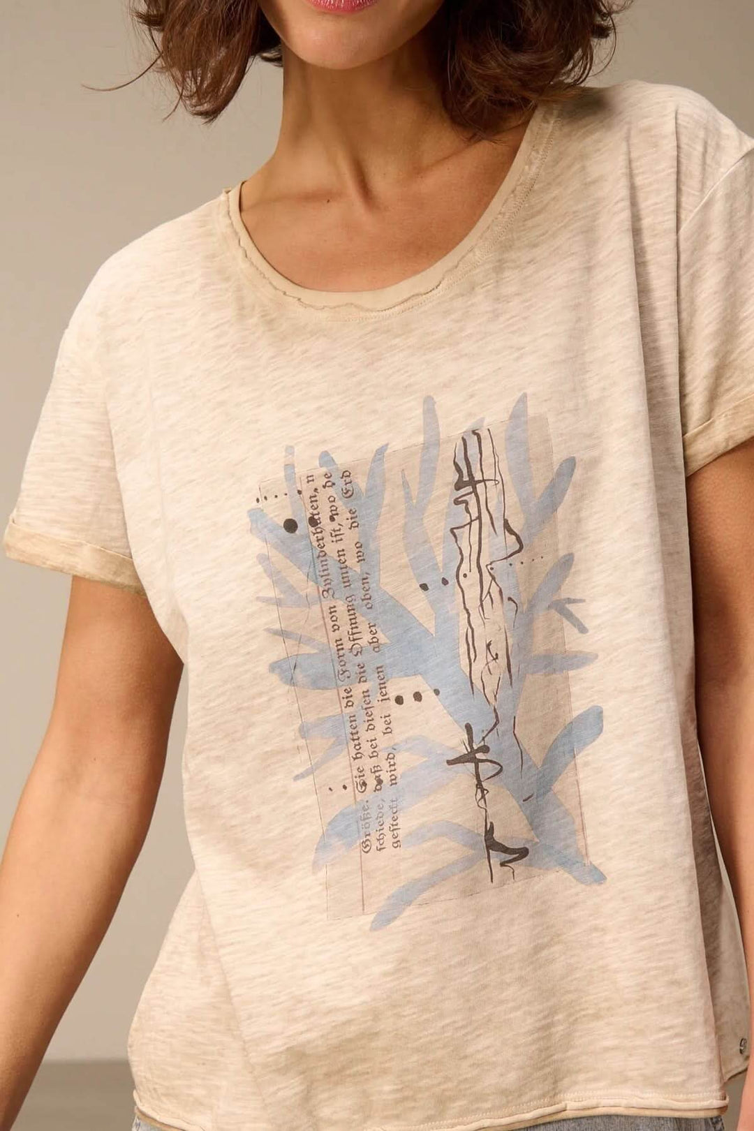 Femme portant un T-shirt à manches courtes coupe décontractée avec motif feuille bleue. Silhouette fluide, tissu doux et respirant.