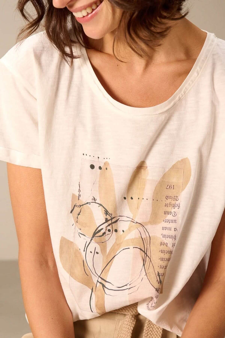Femme portant un T-shirt à manches courtes coupe décontractée avec imprimé graphique sur fond beige.