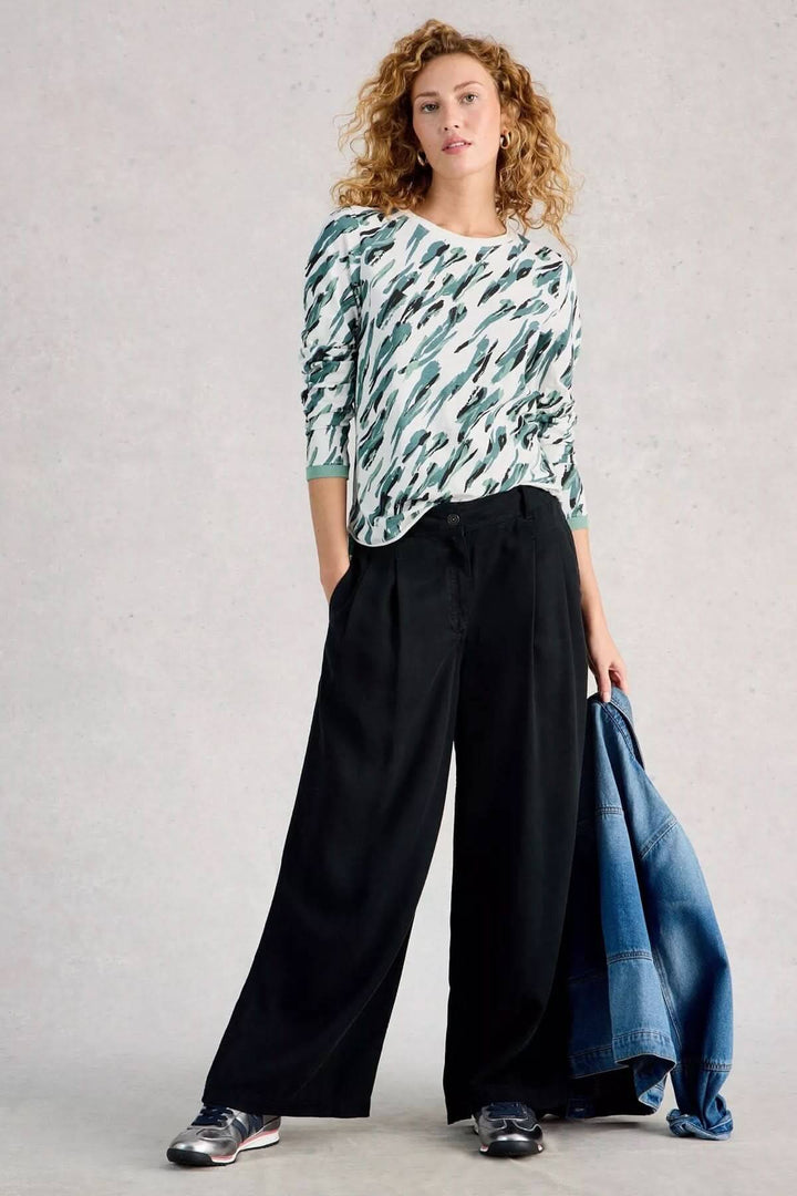 Femme portant le T-shirt à manches longues Clara au design simple et confortable, idéal pour le quotidien, avec un pantalon noir et une veste en jean.