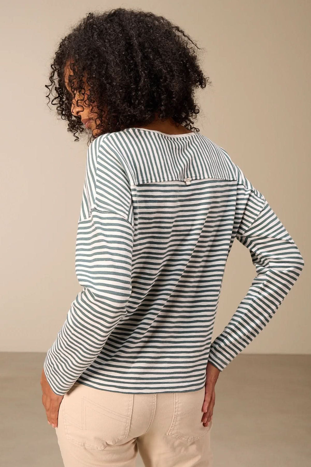 Femme portant un t-shirt à manches longues rayé col rond, avec épaules tombantes et motif rayé, vue de dos.