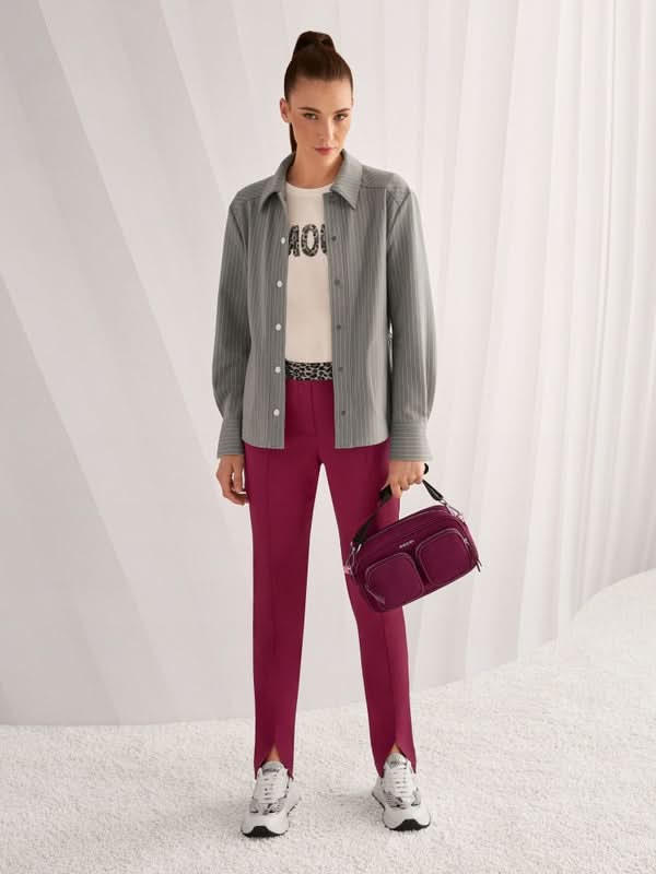 Femme portant un T-shirt à paillettes avec slogan Amour, chemise grise, pantalon fuchsia et sac à main pour un look moderne et décontracté.