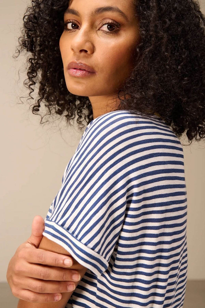 Femme portant un T-shirt rayé manches courtes style raglan, coupe confortable et moderne idéale pour une tenue décontractée.