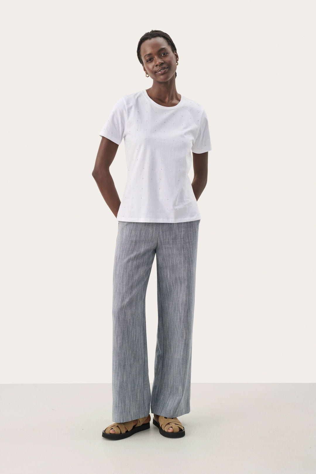 Femme portant un t-shirt blanc simple et un pantalon rayé, style décontracté et élégant.