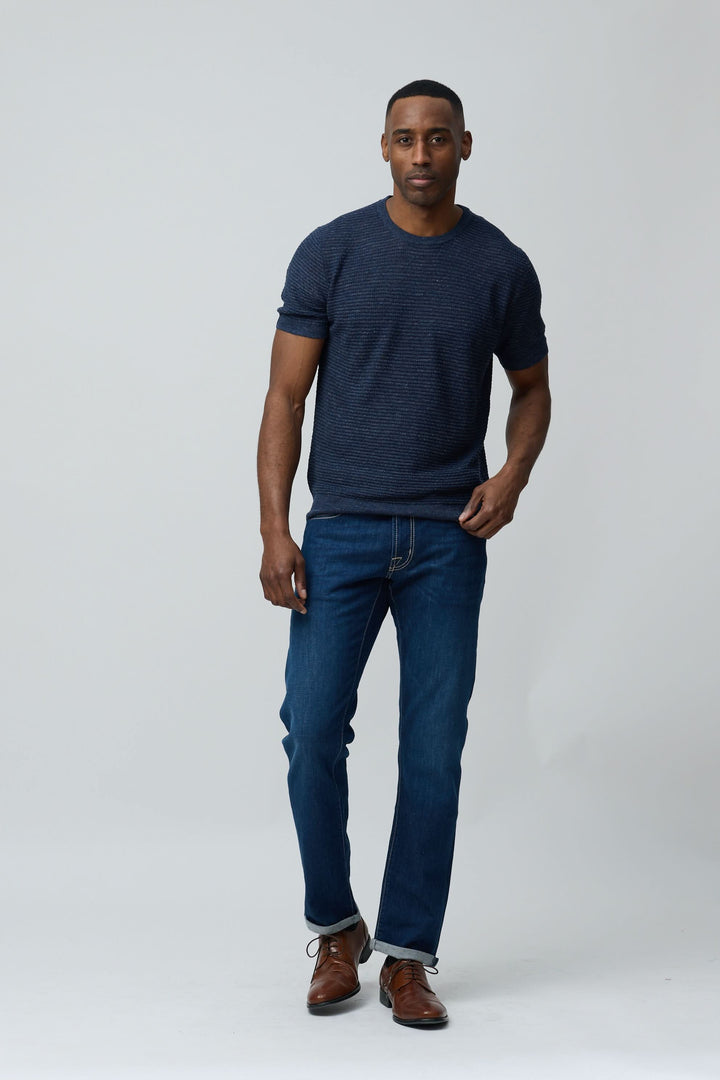 Homme portant un T-shirt texturé en lin et soie avec jean et chaussures, allure moderne et épurée