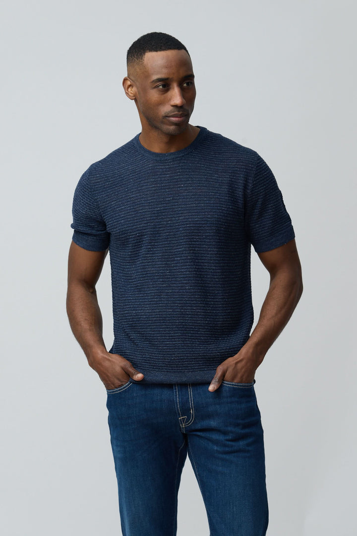 Homme portant un T-shirt texturé en lin et soie bleu marine, coupe ajustée, avec manches courtes. Décris moi le produit en français.