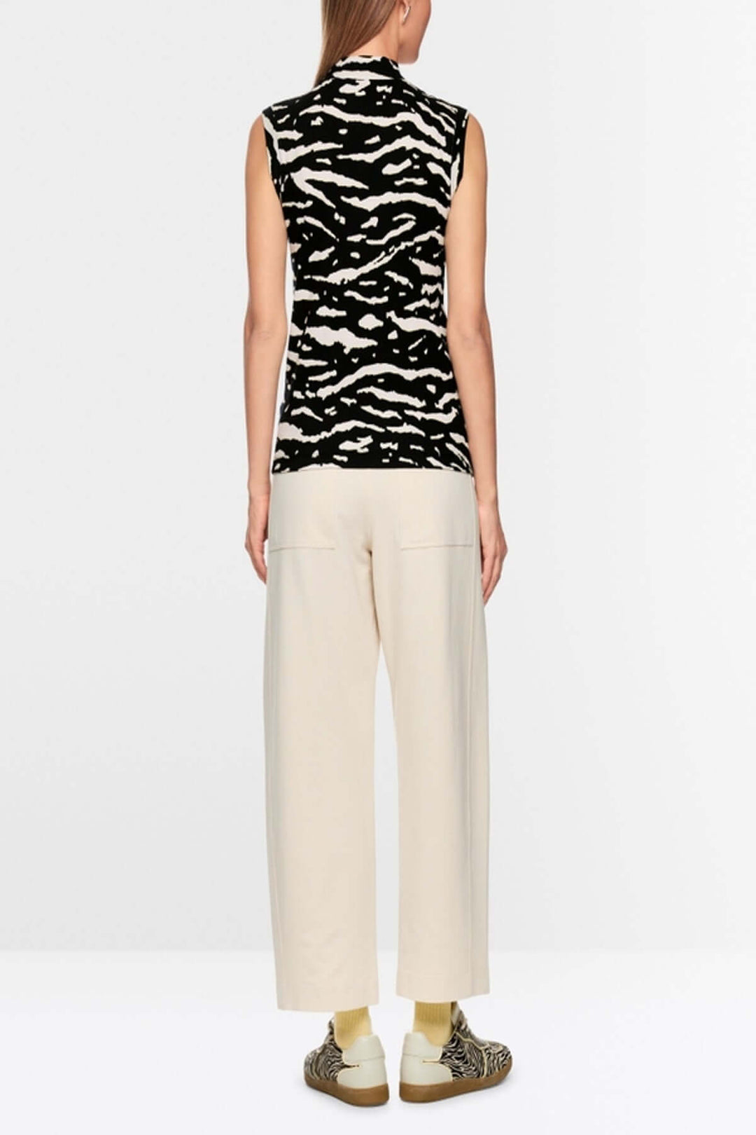 Top avec imprimé animalier sans manches, col montant et fine maille côtelée, vu de dos, sur mannequin portant un pantalon clair et baskets.