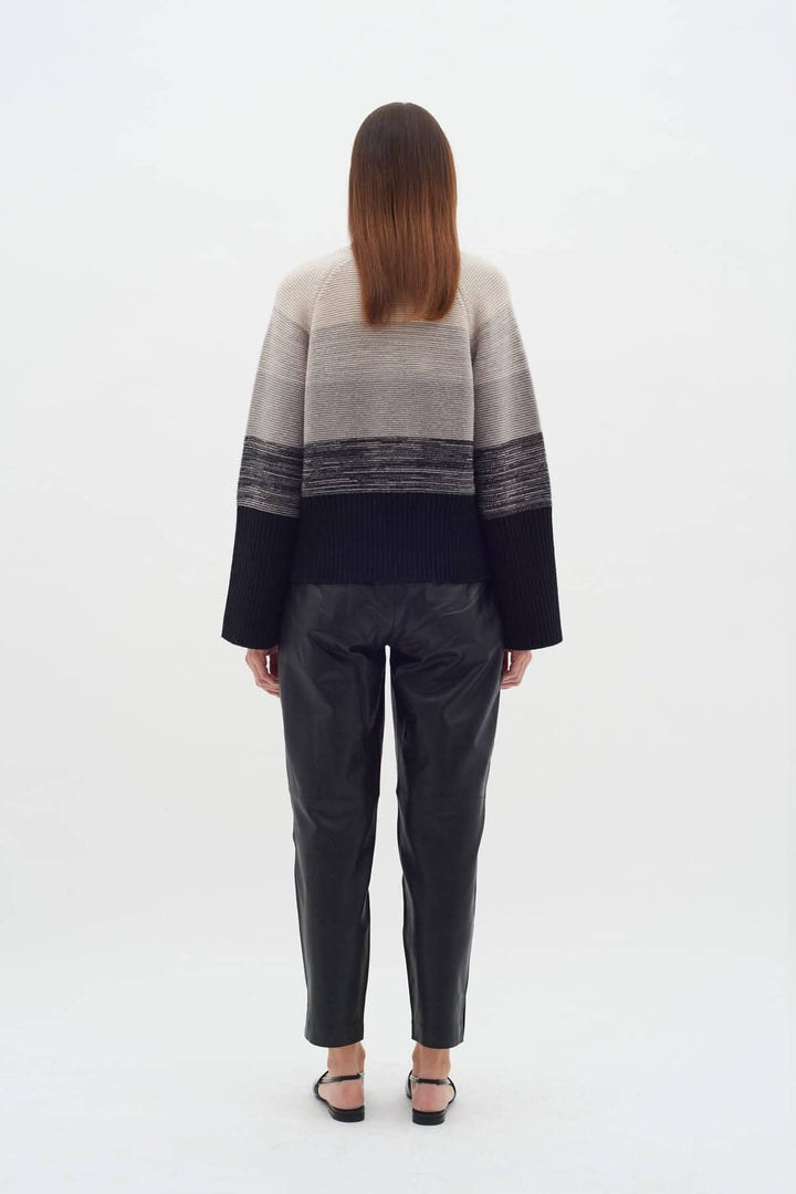 Vue arrière du Tricot Kaxy, pull côtelé extensible à rayures neutres, porté avec un pantalon en cuir.
