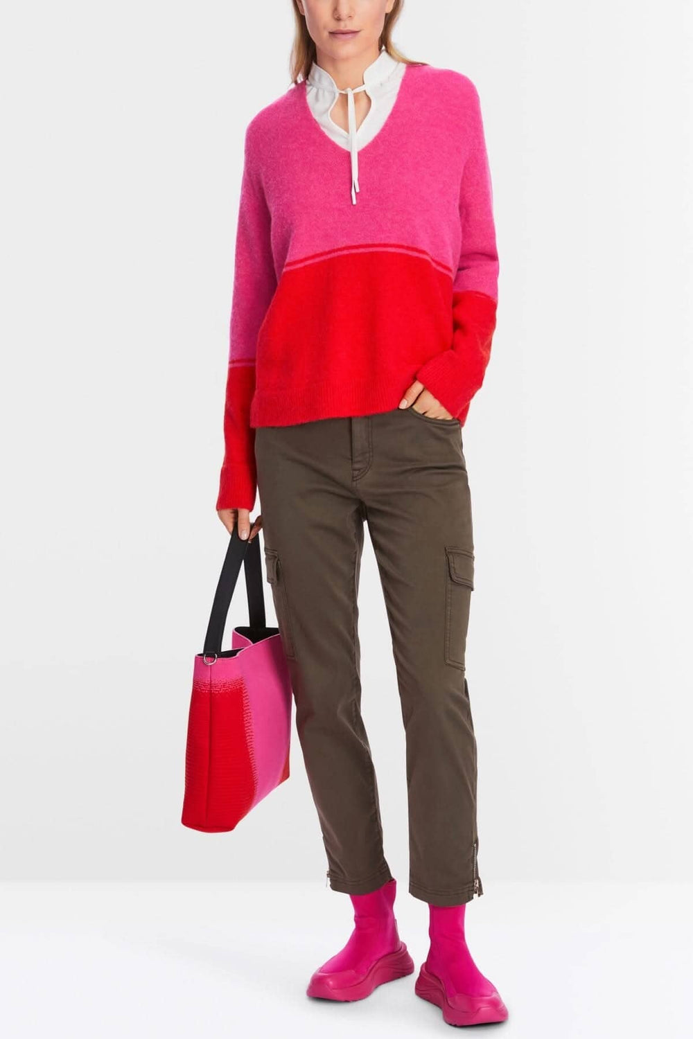Tricot bicolore rouge et rose, encolure en V, porté avec un pantalon cargo et des chaussettes roses.