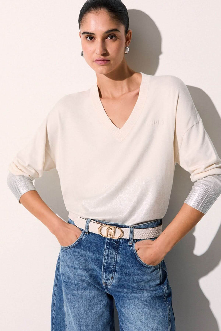 Femme portant un tricot col en V à manches trois-quarts avec poignets contrastants, coupe fluide et confortable.