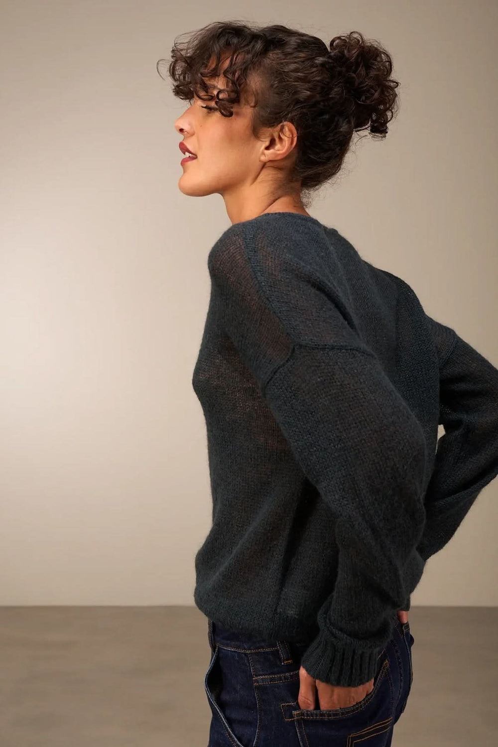 Femme portant un tricot doux et transparent bleu, coupe décontractée, avec boutonnière décorative, style automnal avec jean.