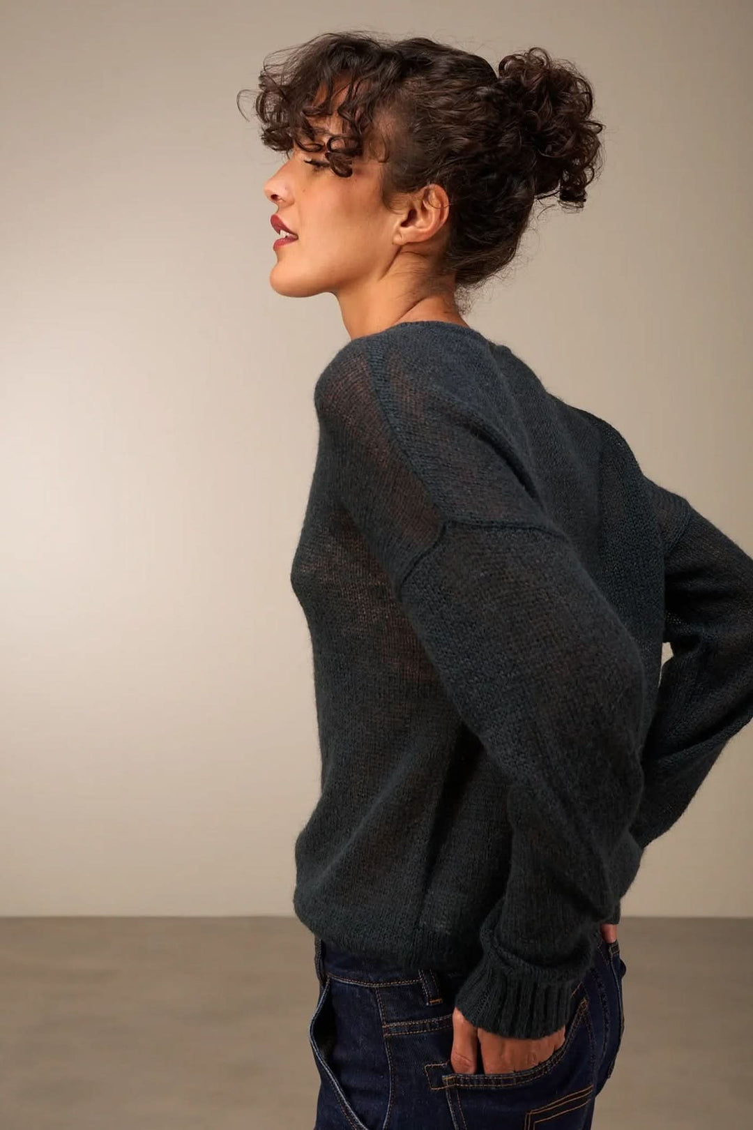 Femme portant un tricot doux et transparent bleu, coupe décontractée, avec boutonnière décorative, style automnal avec jean.