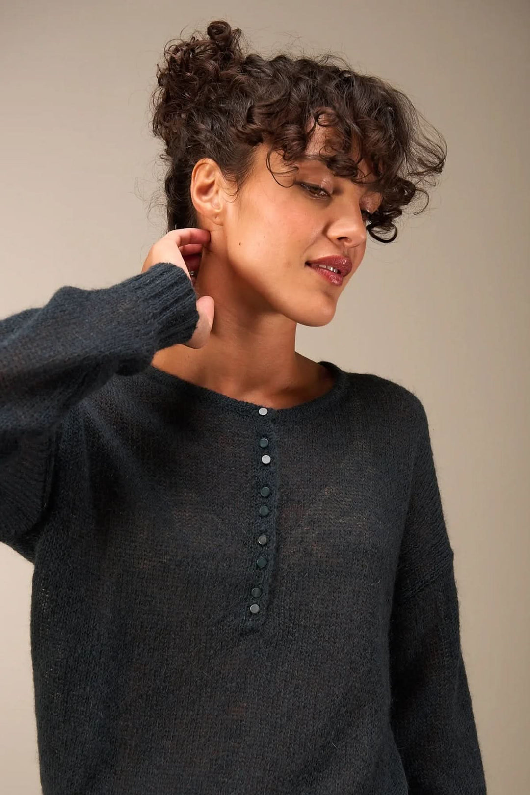 Femme portant un tricot doux et transparent avec patte de boutonnage, coupe décontractée et confortable.