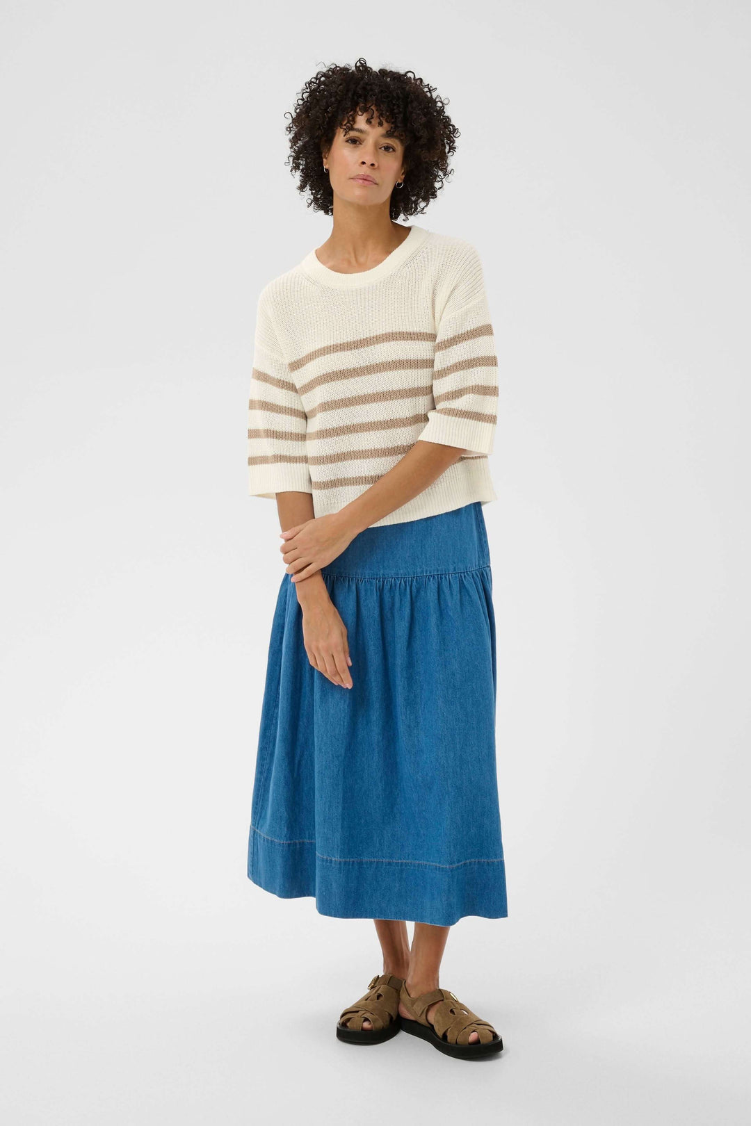 Femme portant un Tricot lin et coton Aliza à manches courtes, maille ajourée, motif rayé, tenue décontractée avec jupe bleue.