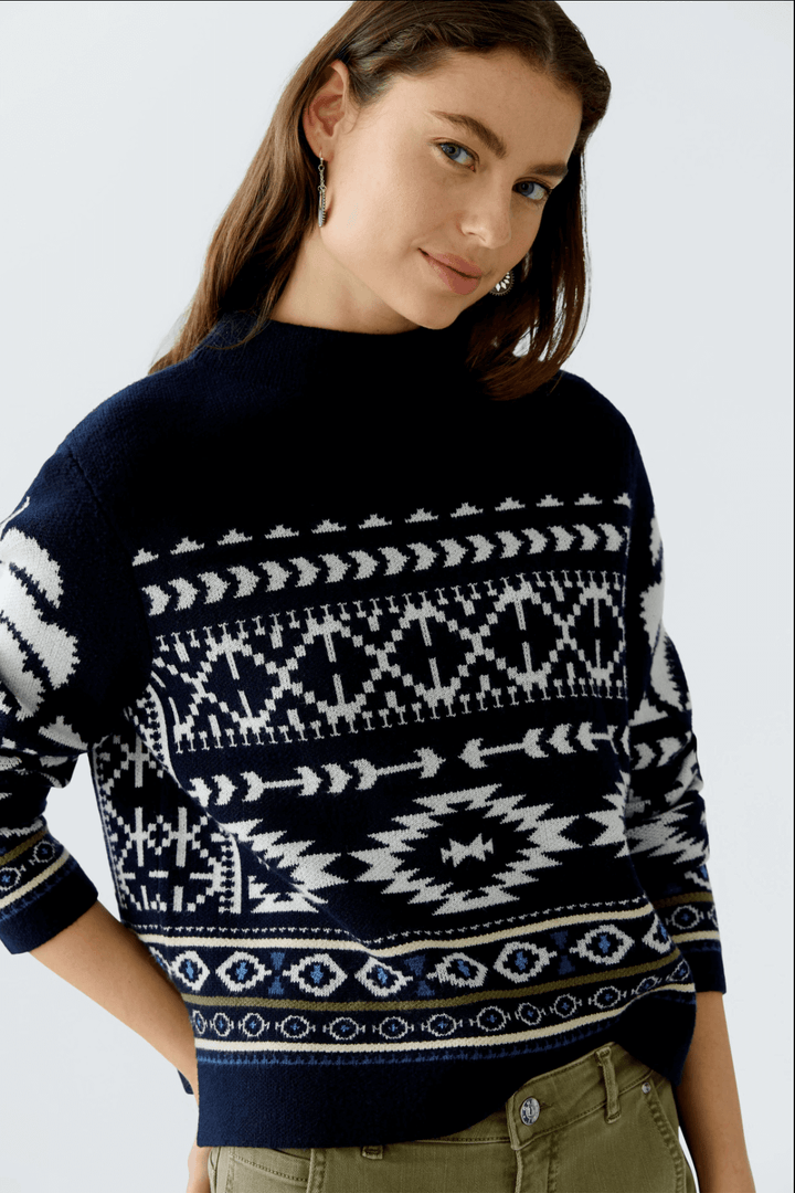 Femme portant un tricot motif norvégien avec col montant et manches longues, look hivernal élégant.