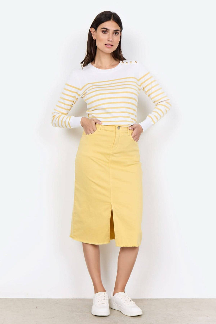 Femme portant un tricot rayé à encolure ronde et jupe jaune, look élégant et décontracté.