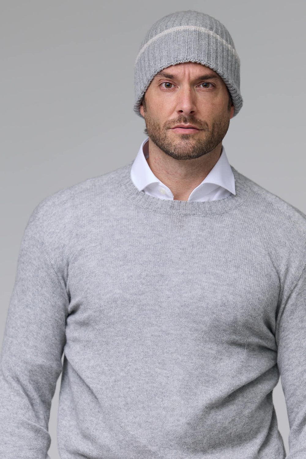 Homme portant une tuque en tricot côtelé grise, idéale pour les journées froides, offrant confort et style avec un tricot extensible.