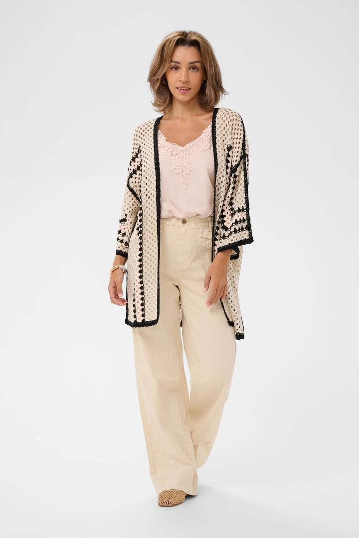 Femme portant une Veste Free ouverte en crochet avec motif ajouré et bordures contrastantes, tenue bohème élégante.
