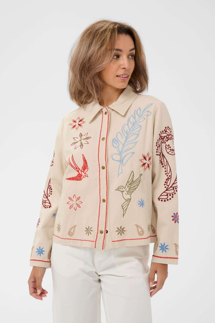 Veste Rosetta brodée à col chemise avec broderies artistiques, col structuré et fermeture boutonnée, portée par une femme.