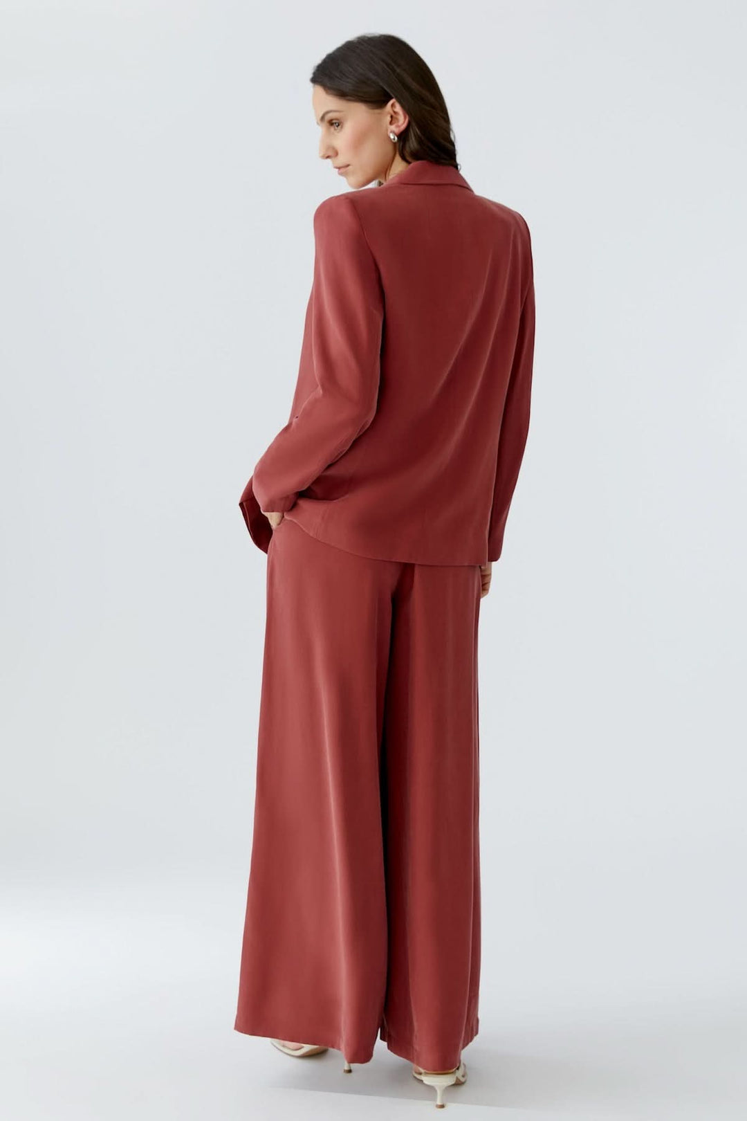 Femme portant une veste blazer structurée croisée élégante de couleur rouille, vue de dos, parfaite pour un look professionnel chic.