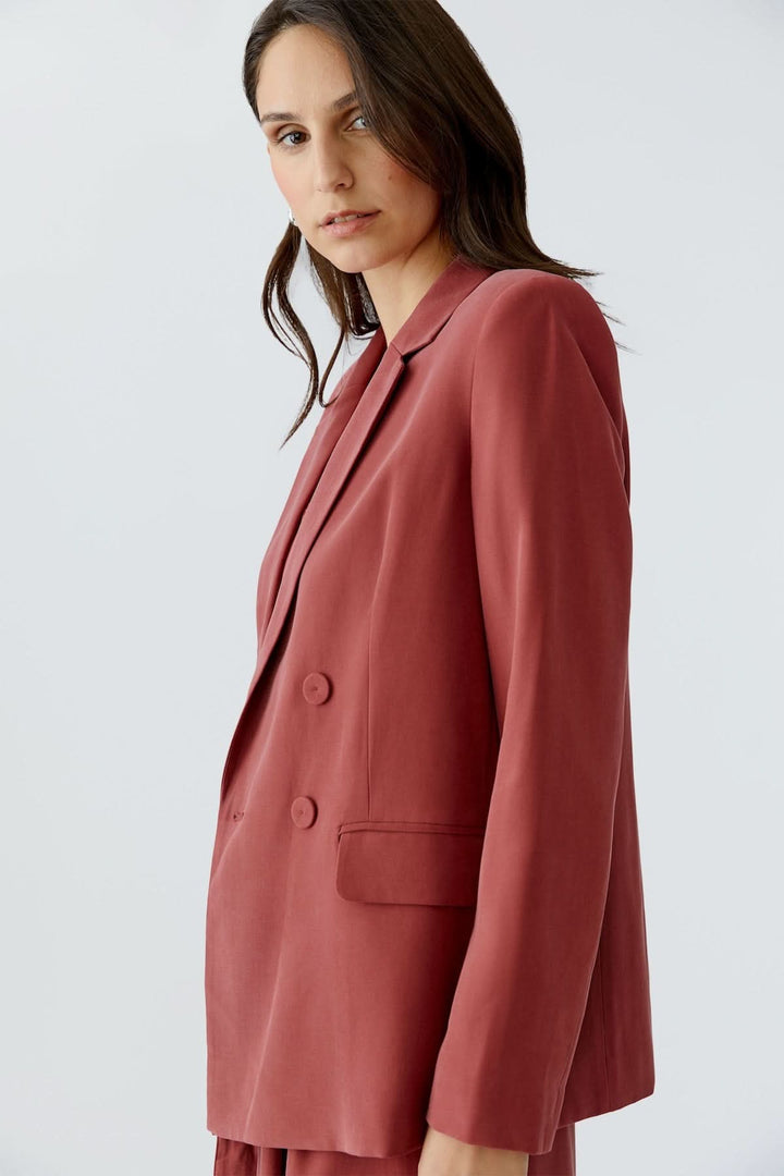 Veste blazer structurée croisée couleur rouge portée par une femme, coupe droite et double boutonnage, look moderne et élégant.