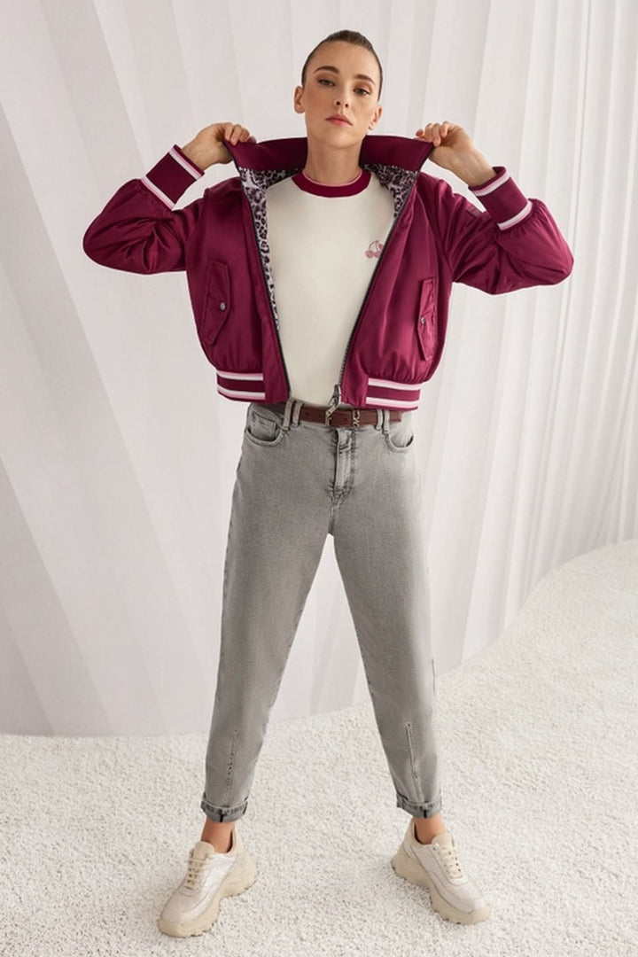 Femme portant une veste bomber réversible avec intérieur imprimé léopard, manches amples et poignets contrastés.