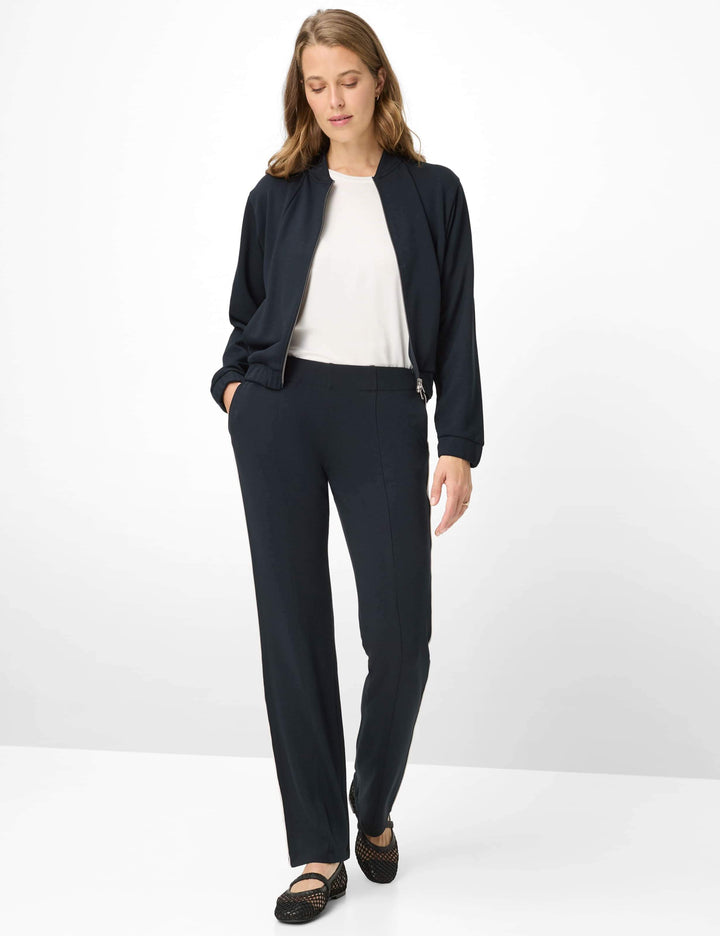 Femme portant une Veste bomber zipée BECKY L. noire, style minimaliste et contemporain, avec fermeture zippée centrale.