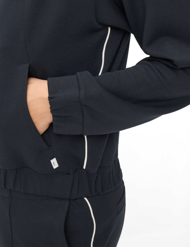 Détail de la veste bomber zippée BECKY L. noire avec lignes blanches, coupe courte, mettant en valeur un style moderne et minimaliste.