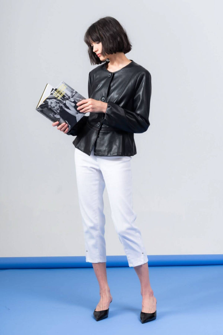 Femme portant une veste péplum boutonnée noire en PU, tenue chic avec un livre en mains.