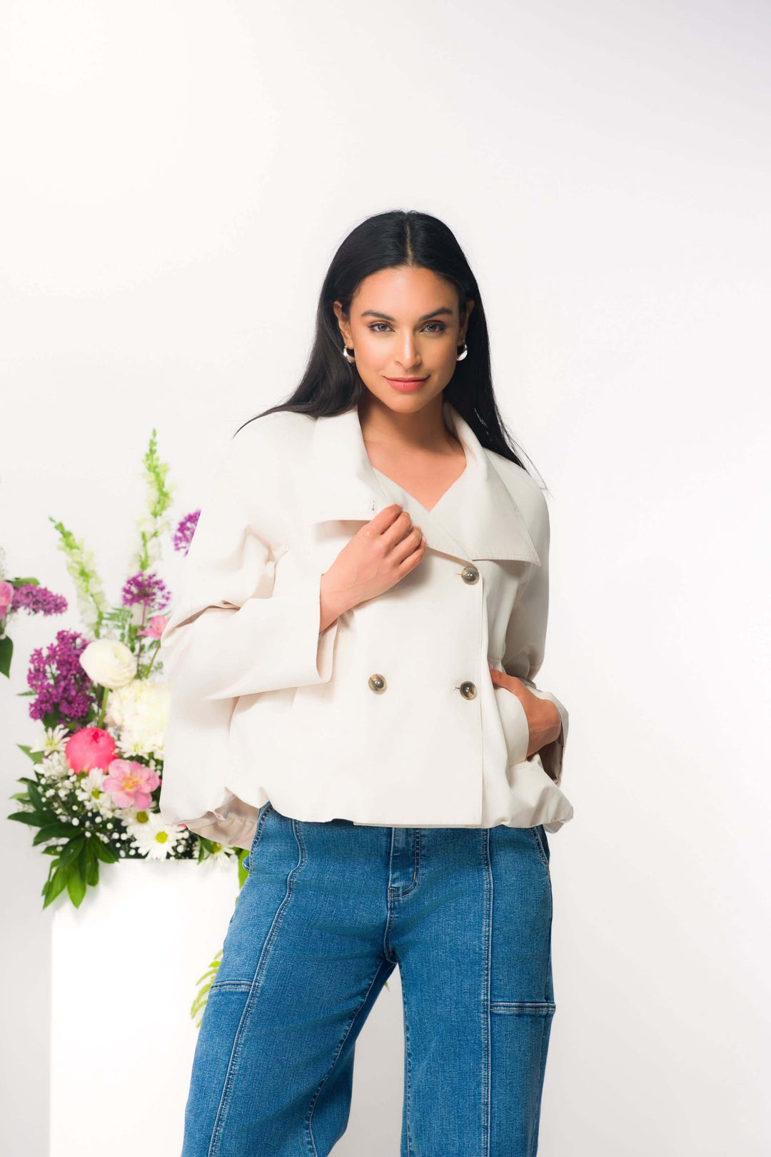 Femme portant une veste courte élégante à double boutonnage avec un fond de fleurs, idéale pour un style moderne et féminin.