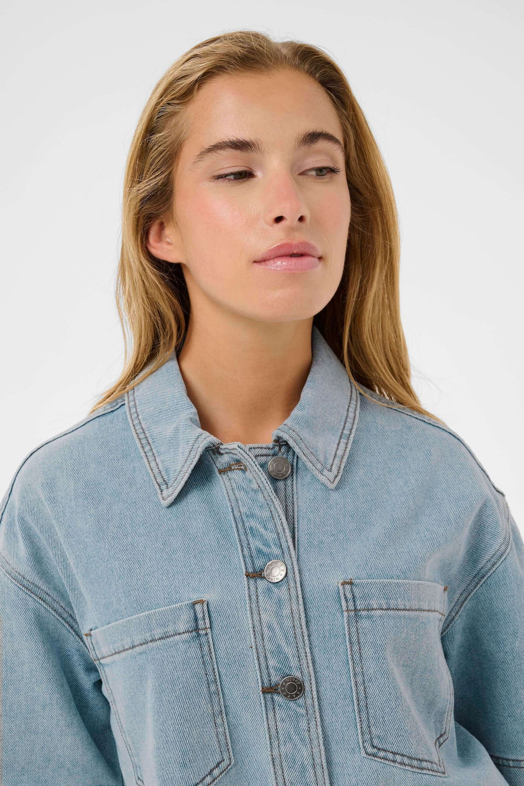 Veste courte en denim à manches courtes avec col classique, poches poitrine et fermeture boutonnée sur mannequin.