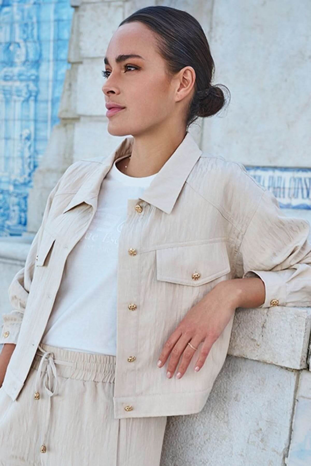 Modèle portant une veste courte en jacquard texturé avec boutons dorés et col classique, style moderne.