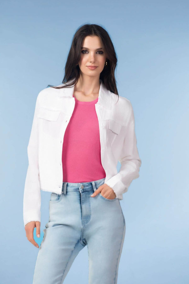 Femme portant une veste courte à finitions effilochées, avec un haut rose et un jean clair.